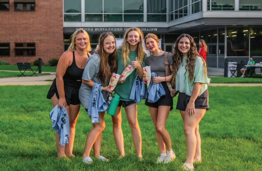 A group of students smiling outdoors in front of the 健康 and 娱乐 Center.